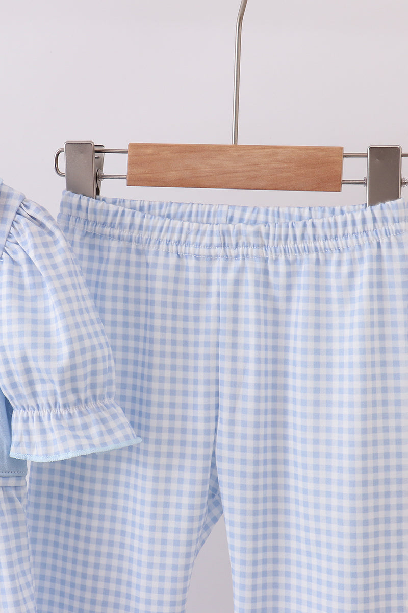 Blue and white checkered shorts on a hanger against a light background
