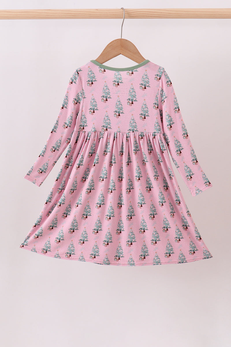 Pink dress with tree pattern on a hanger against a white background
