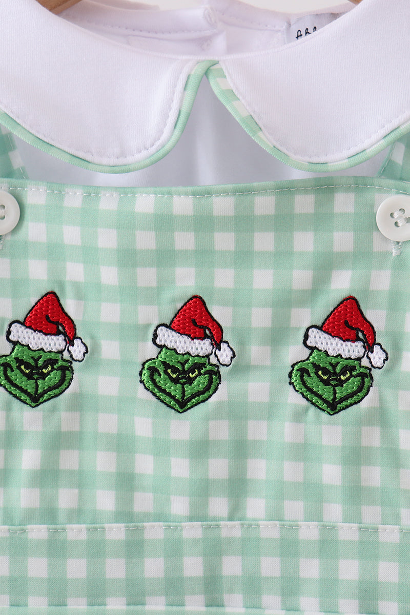 Green checkered dress with embroidered Grinch faces wearing Santa hats on a white background.