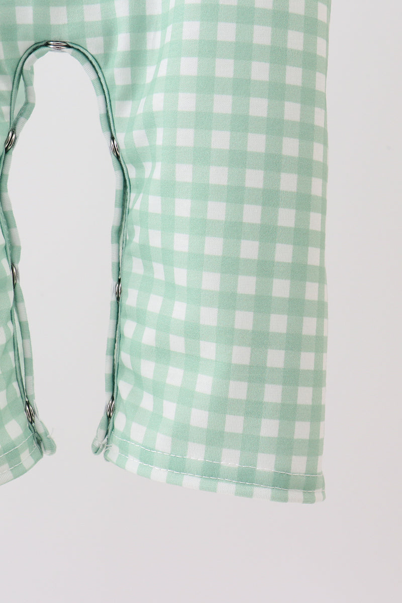 Green and white checkered bag with a strap on a light gray background