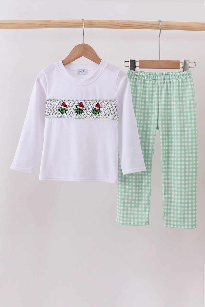 White top with embroidered design and green checkered pants on a hanger against a white background