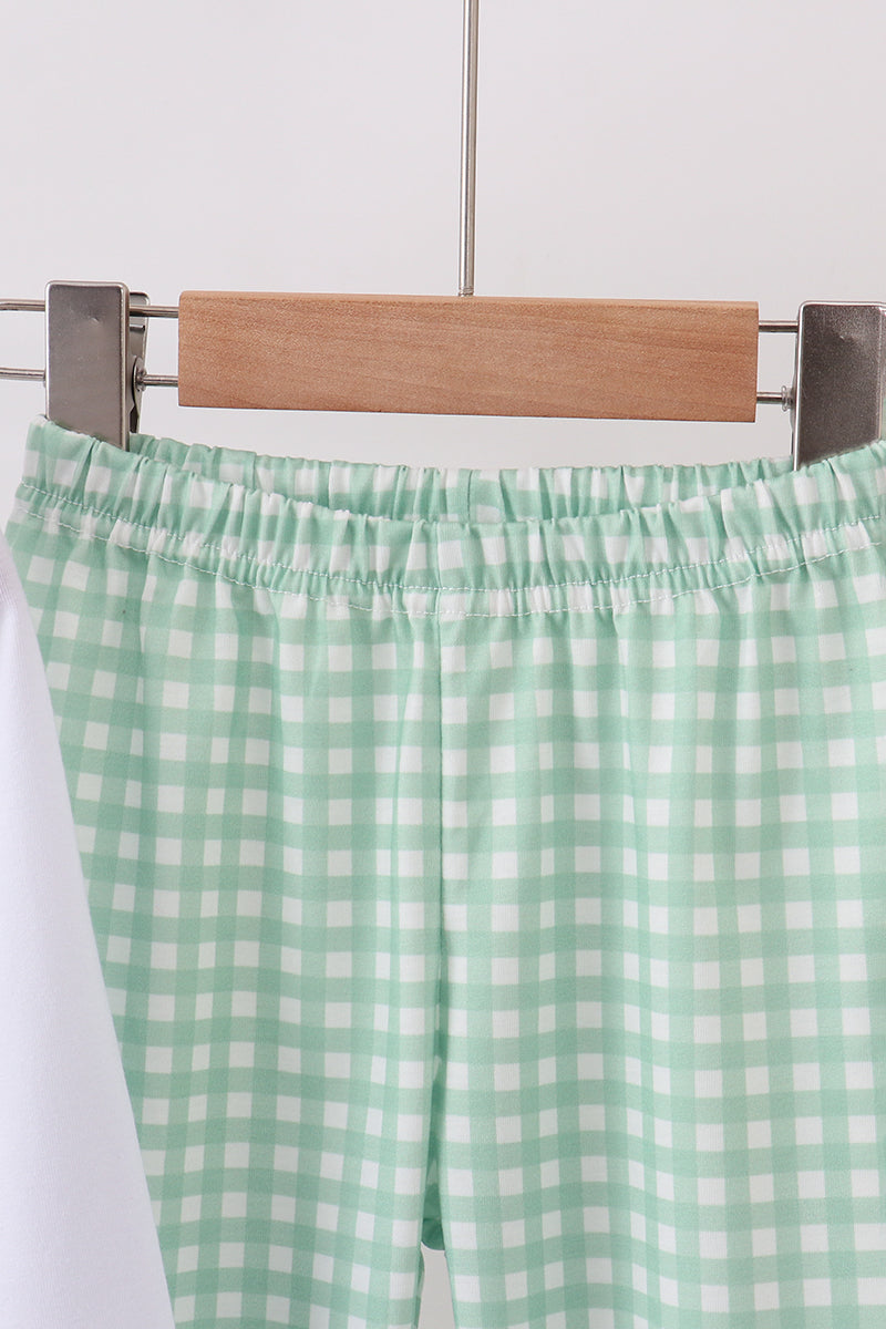 Green and white checkered pants on a hanger against a white background
