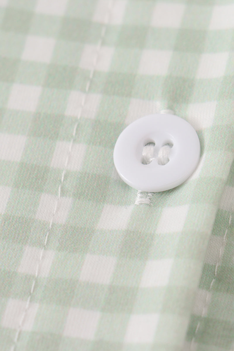 Close-up of a white button on a green checkered fabric background
