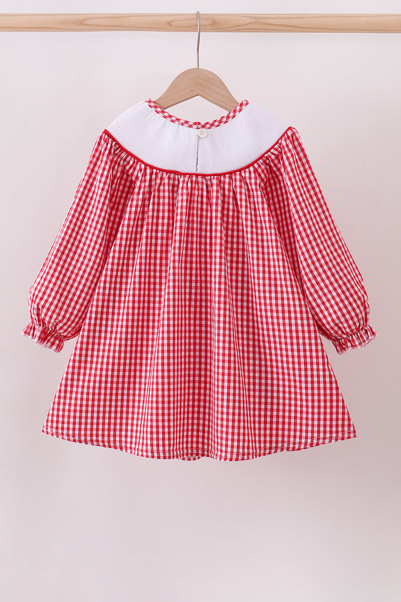 Red and white checkered dress with long sleeves on a wooden hanger against a light background