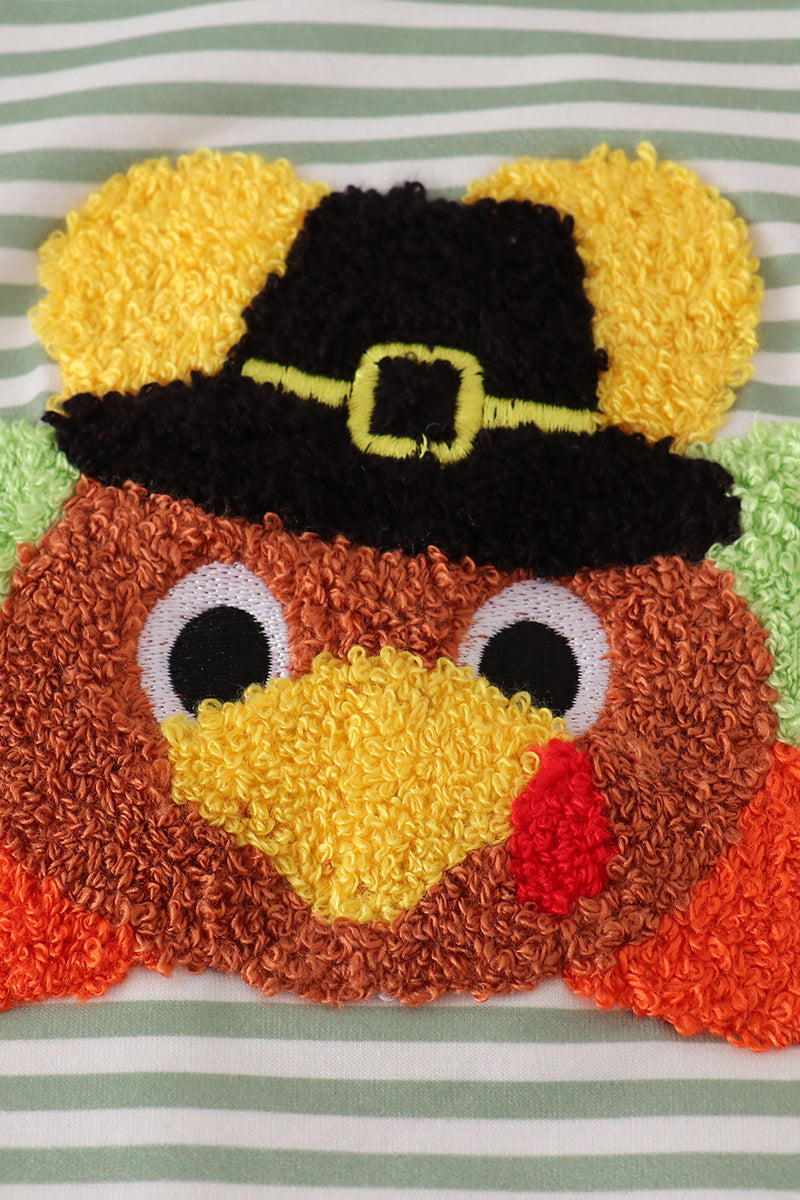 Turkey-shaped pillow with a pilgrim hat on a striped background