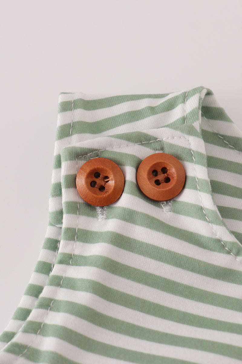 Green and white striped fabric with two wooden buttons on a light gray background