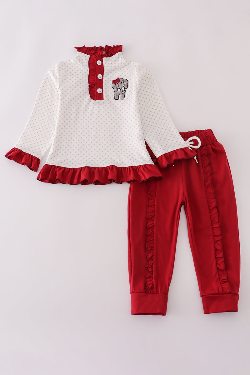 Children's outfit with white top and red pants on a light gray background