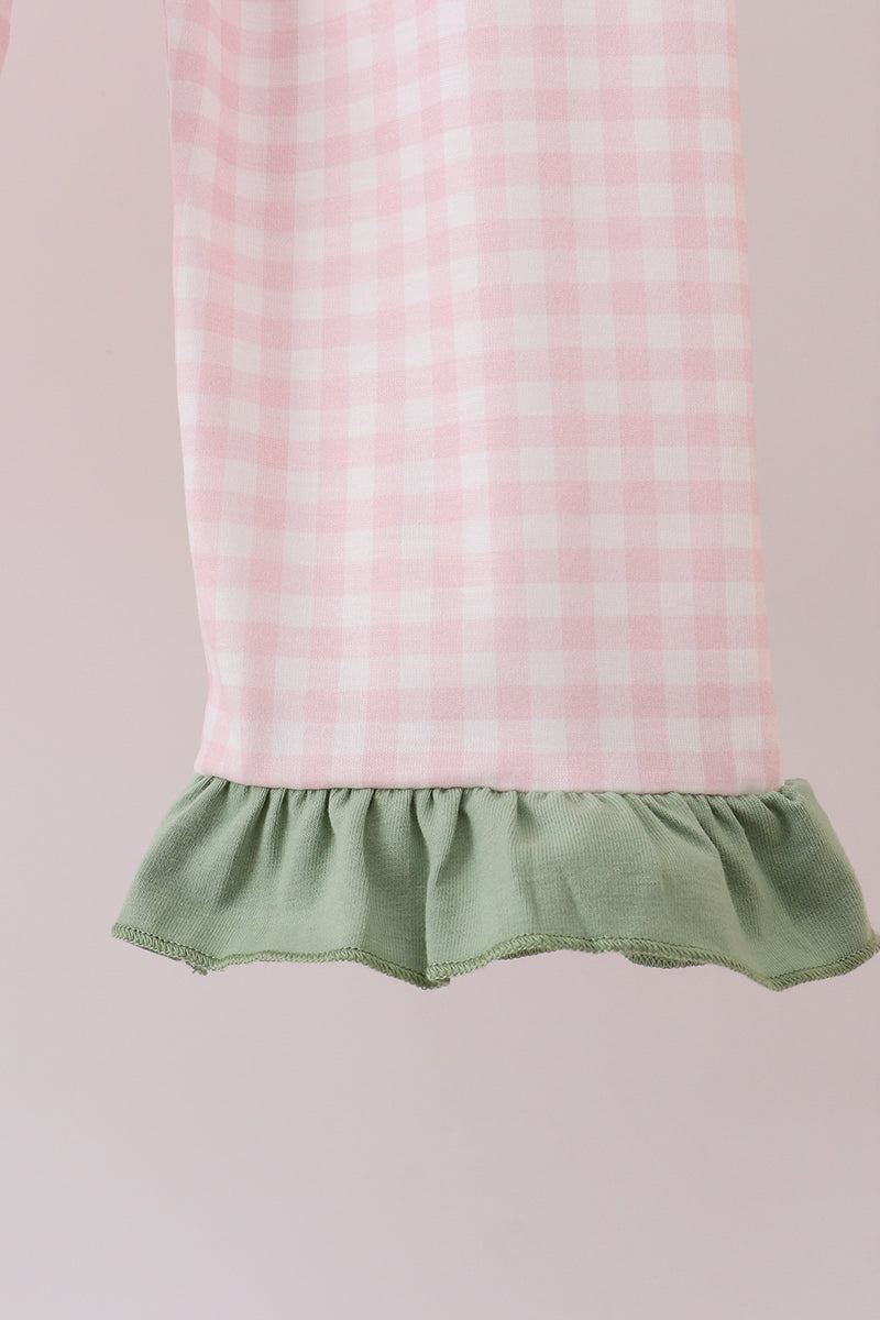 Pink and white checkered dress with green ruffled hem on a pink background