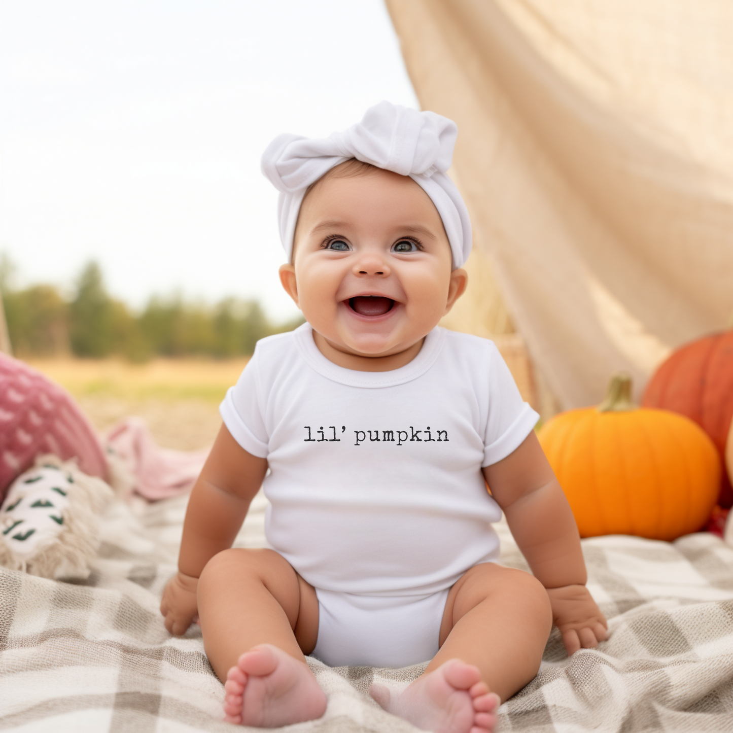 Baby wearing a 'lil' pumpkin' onesie in a field with pumpkins.