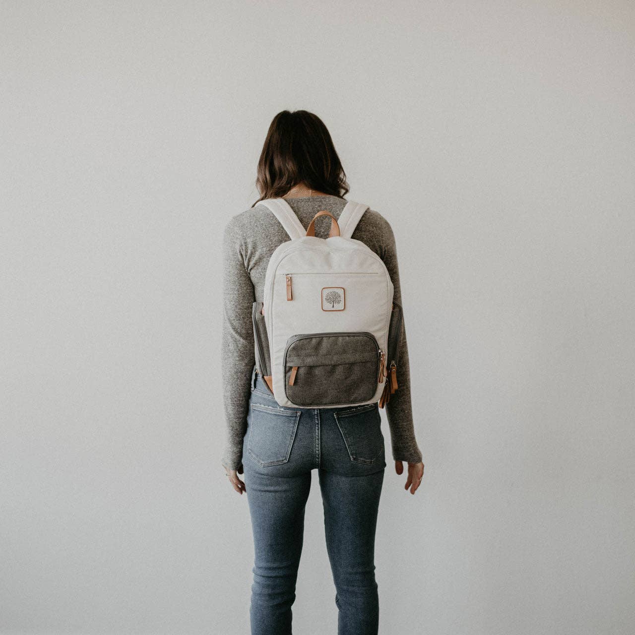 Person wearing a gray and white backpack against a plain background