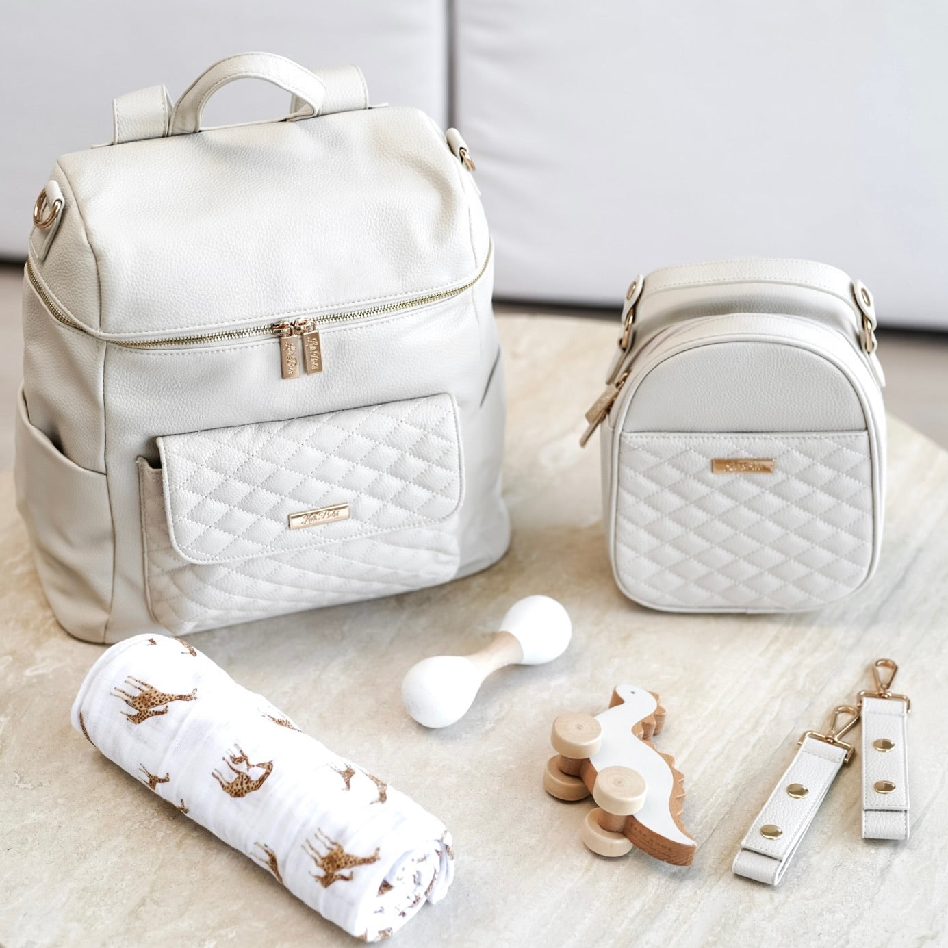 White quilted diaper bag with matching accessories on a light surface