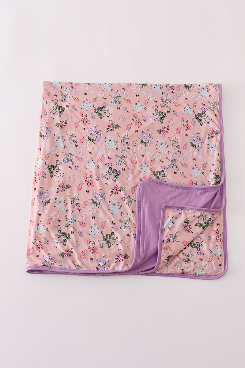 Floral-patterned blanket with a purple border on a light pink background