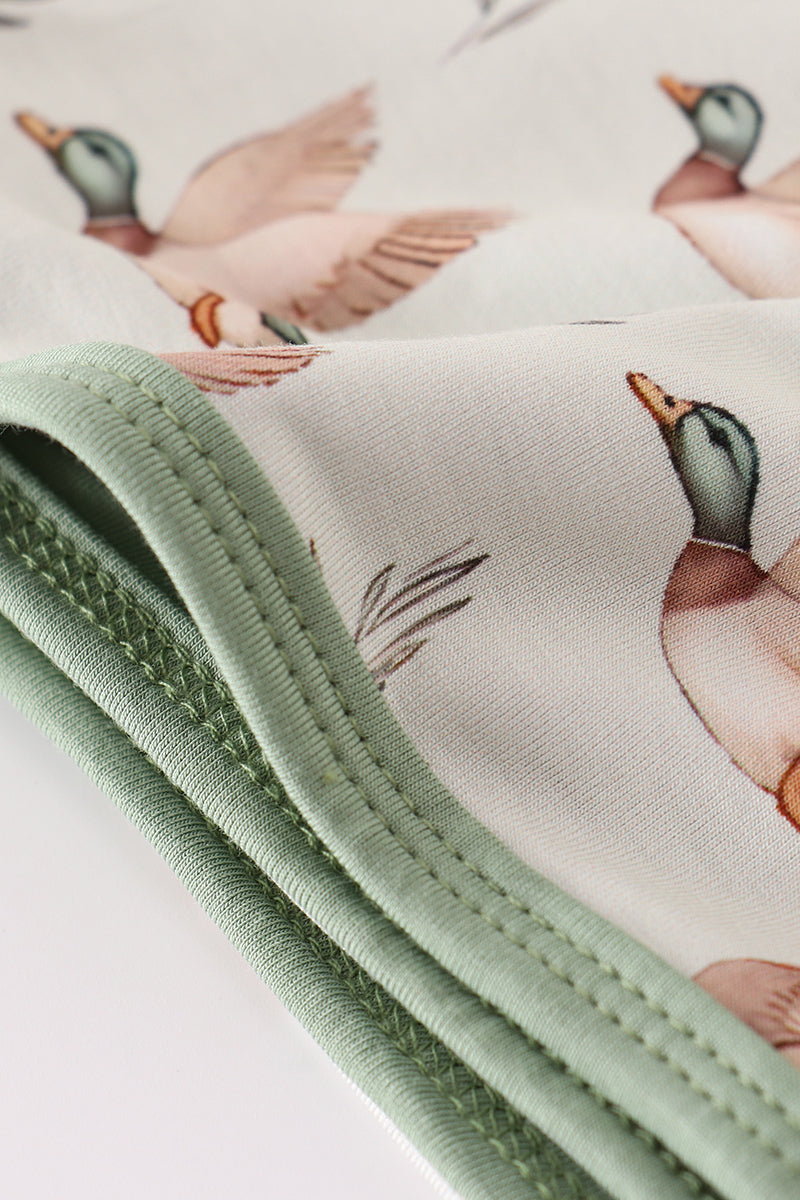 Fabric with duck pattern and green trim on a white background