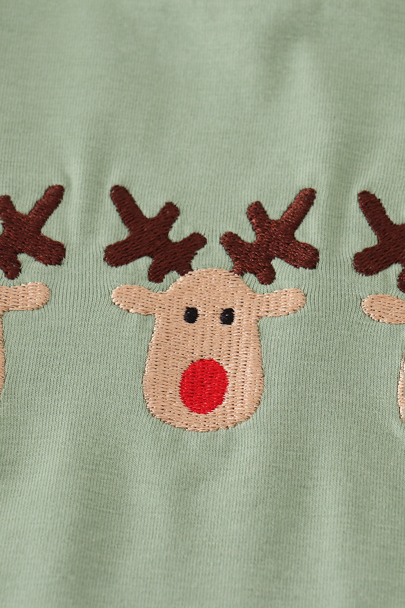 Embroidered reindeer faces on a green fabric background
