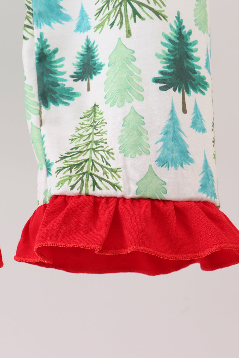 Children's outfit with tree pattern and red ruffle on a plain background