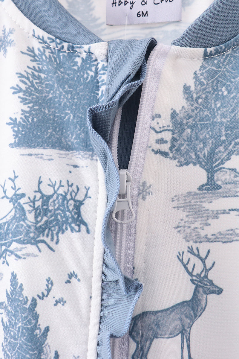 Close-up of a children's outfit with a deer and tree pattern, zipper detail, and size label.