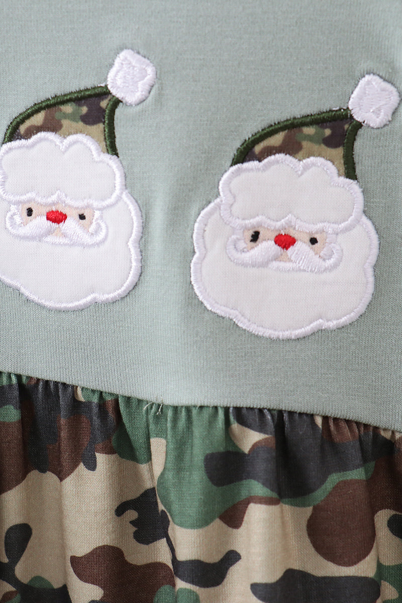 Green fabric with two embroidered Santa Claus faces and a camouflage pattern at the bottom.