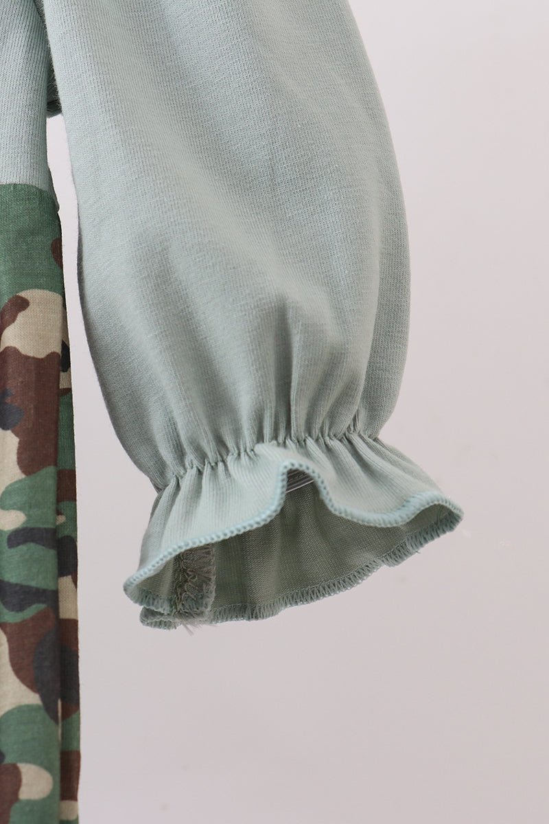 Close-up of green ruffled sleeves with a camouflage pattern on a plain background