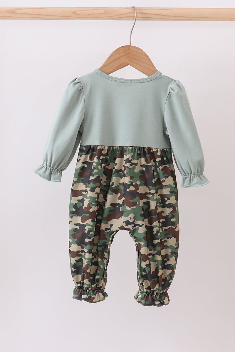 Children's outfit with light blue top and camouflage pants on a hanger against a white background