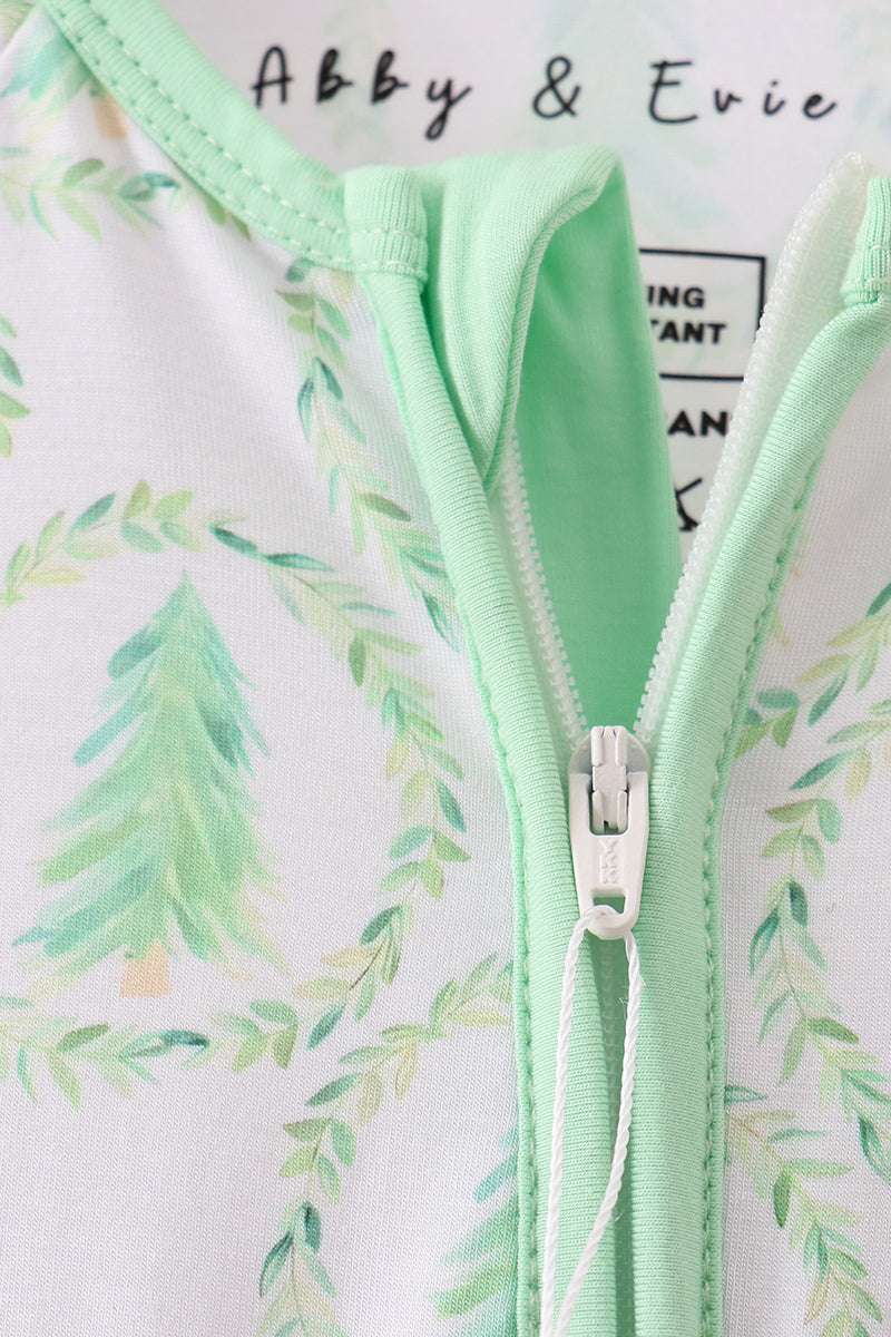 Close-up of a mint green zipper on a garment with a floral pattern in the background.