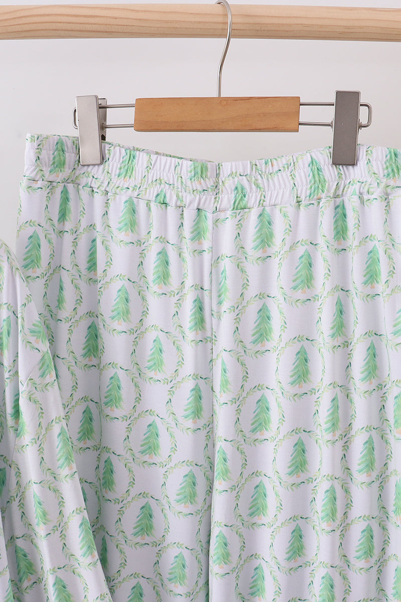 Green patterned pants hanging on a wooden hanger against a white background
