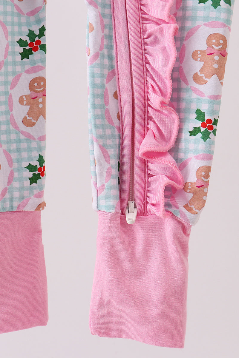 Pink baby romper with gingerbread man and holly design on a light gray background