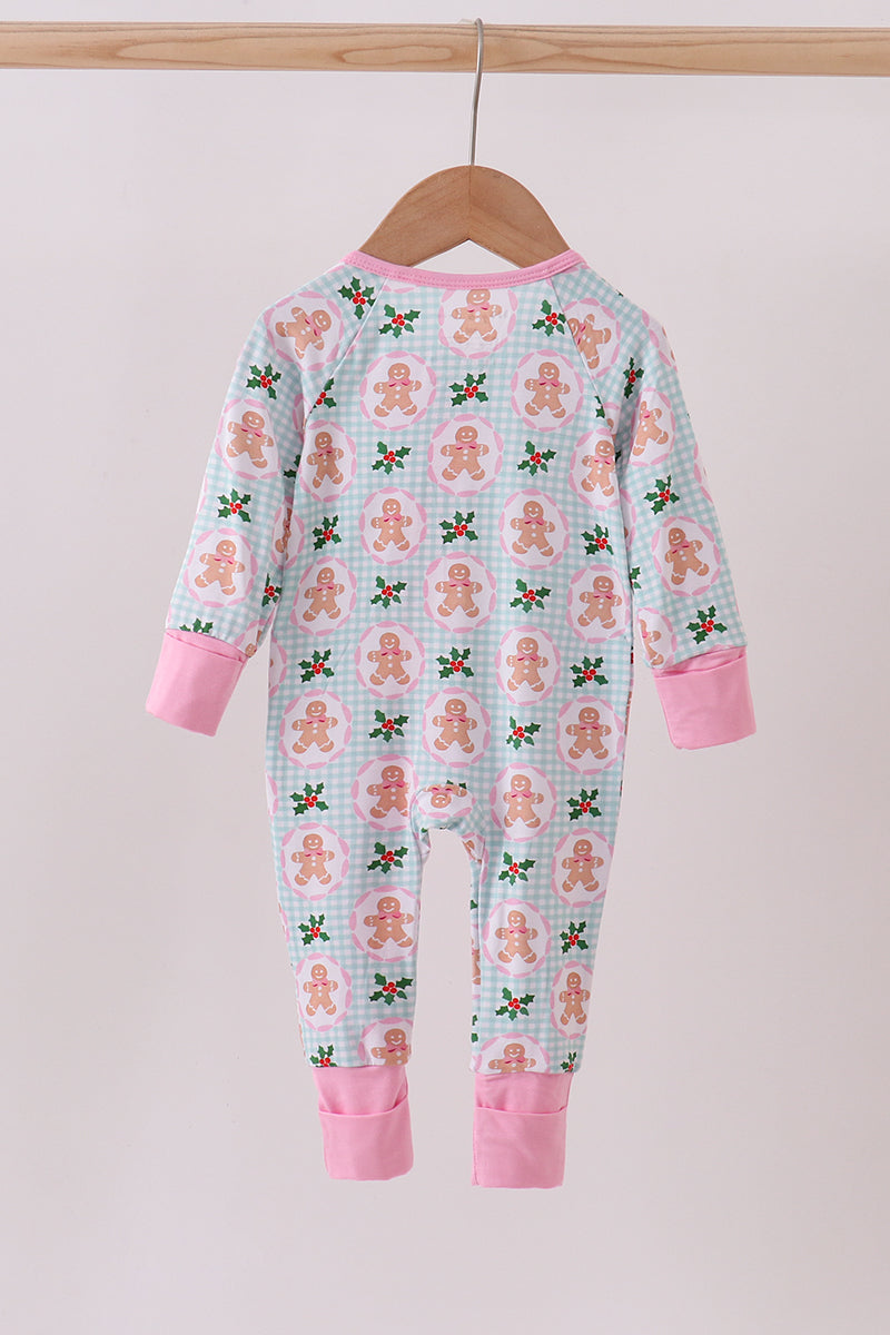Children's onesie with gingerbread man pattern on a hanger against a light pink background