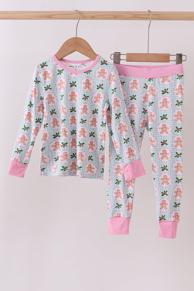Children's pajama set with gingerbread man pattern on a hanger against a white background
