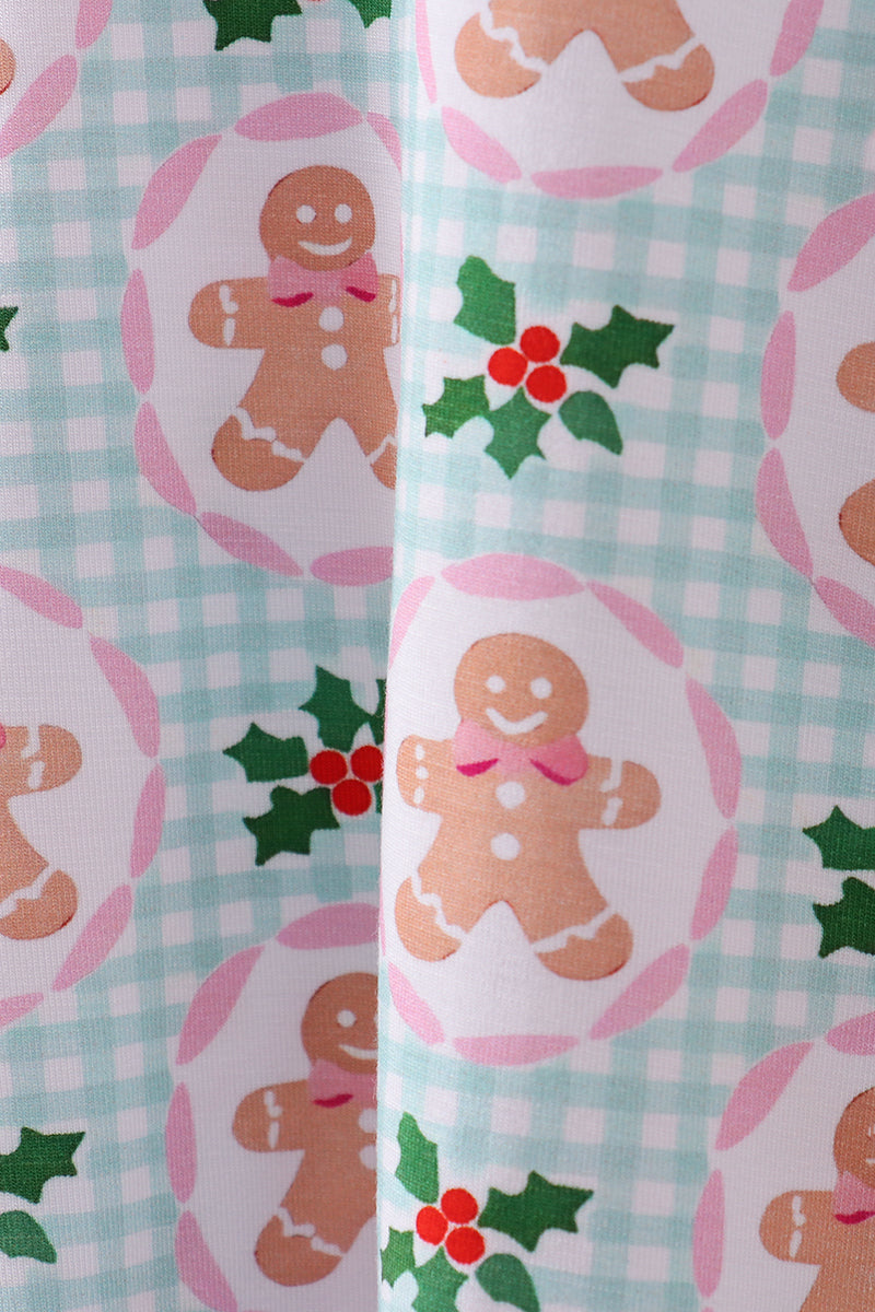 Christmas-themed wrapping paper with gingerbread men and holly leaves on a checkered background.