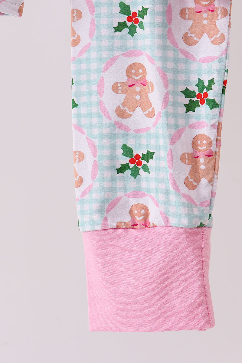 Fabric with gingerbread man and holly pattern on a light blue checkered background, with pink fabric underneath.