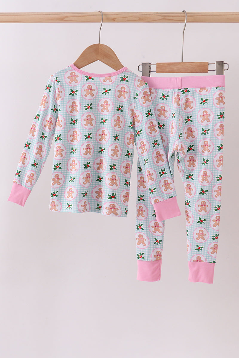 Children's pajama set with gingerbread man pattern on a hanger against a white background