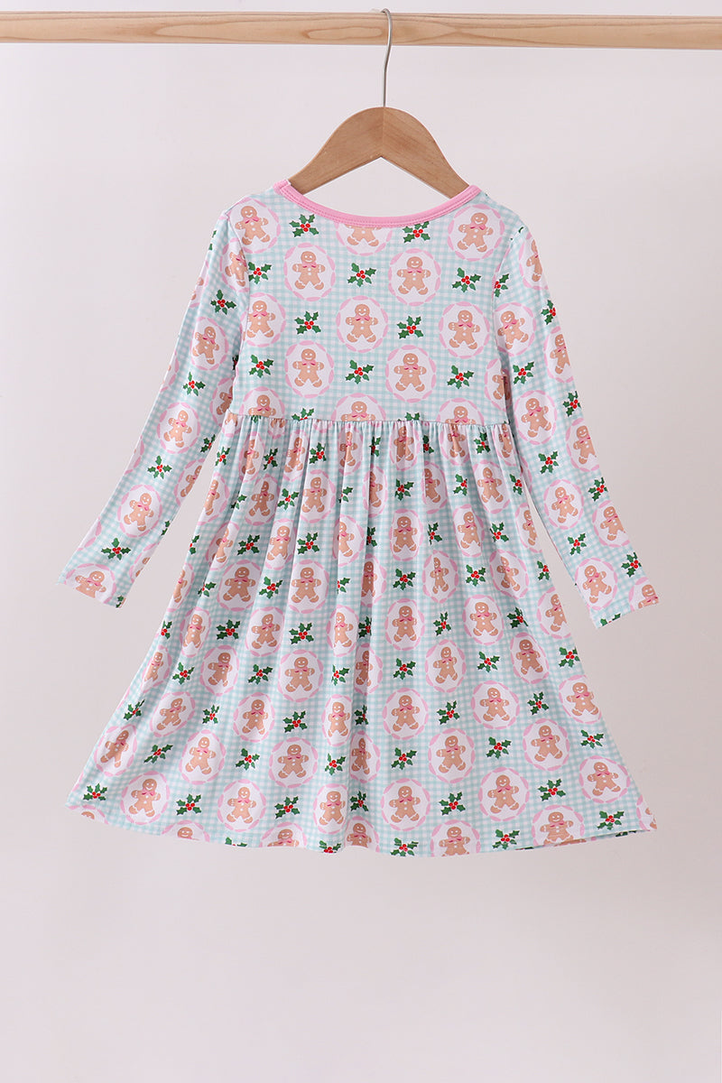 Children's dress with gingerbread man pattern on a hanger against a white background