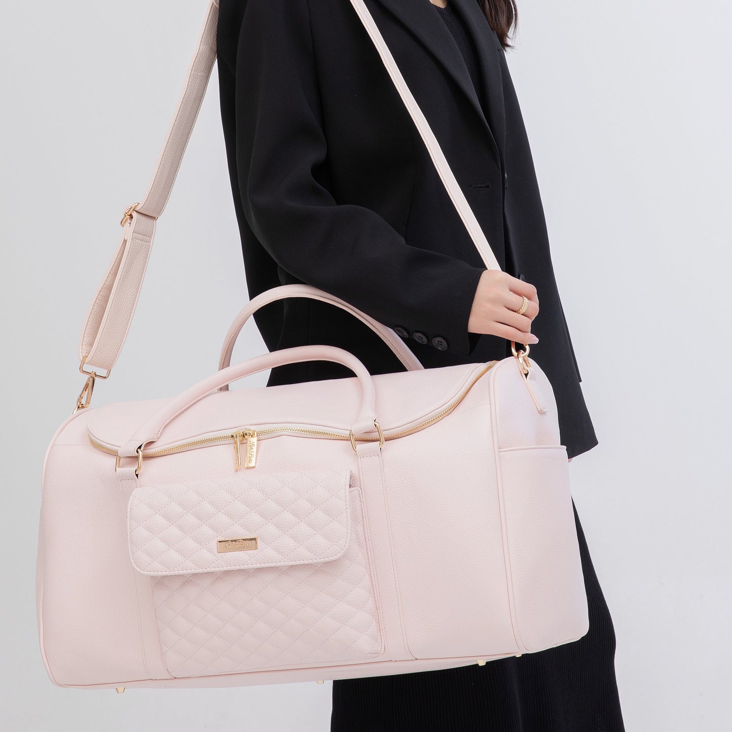 Person holding a light pink handbag with a plain background