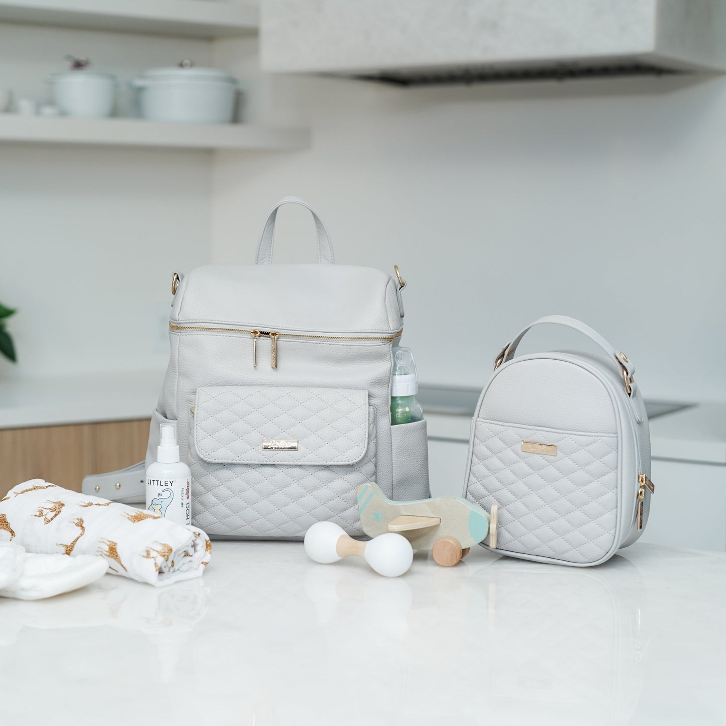 Gray quilted diaper bags on a kitchen counter with baby items.