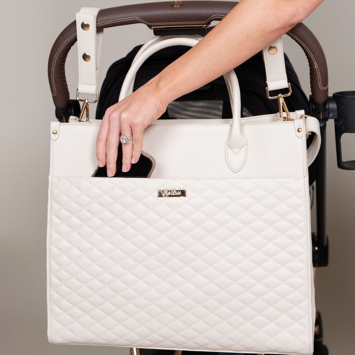 White quilted handbag held by a person with a stroller in the background