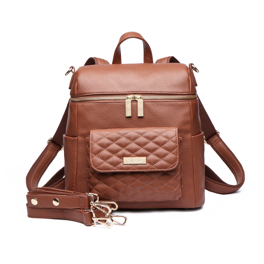 A caramel brown Petit Monaco diaper bag made from vegan leather, featuring a compact design with multiple carrying options, including a backpack and crossbody strap.