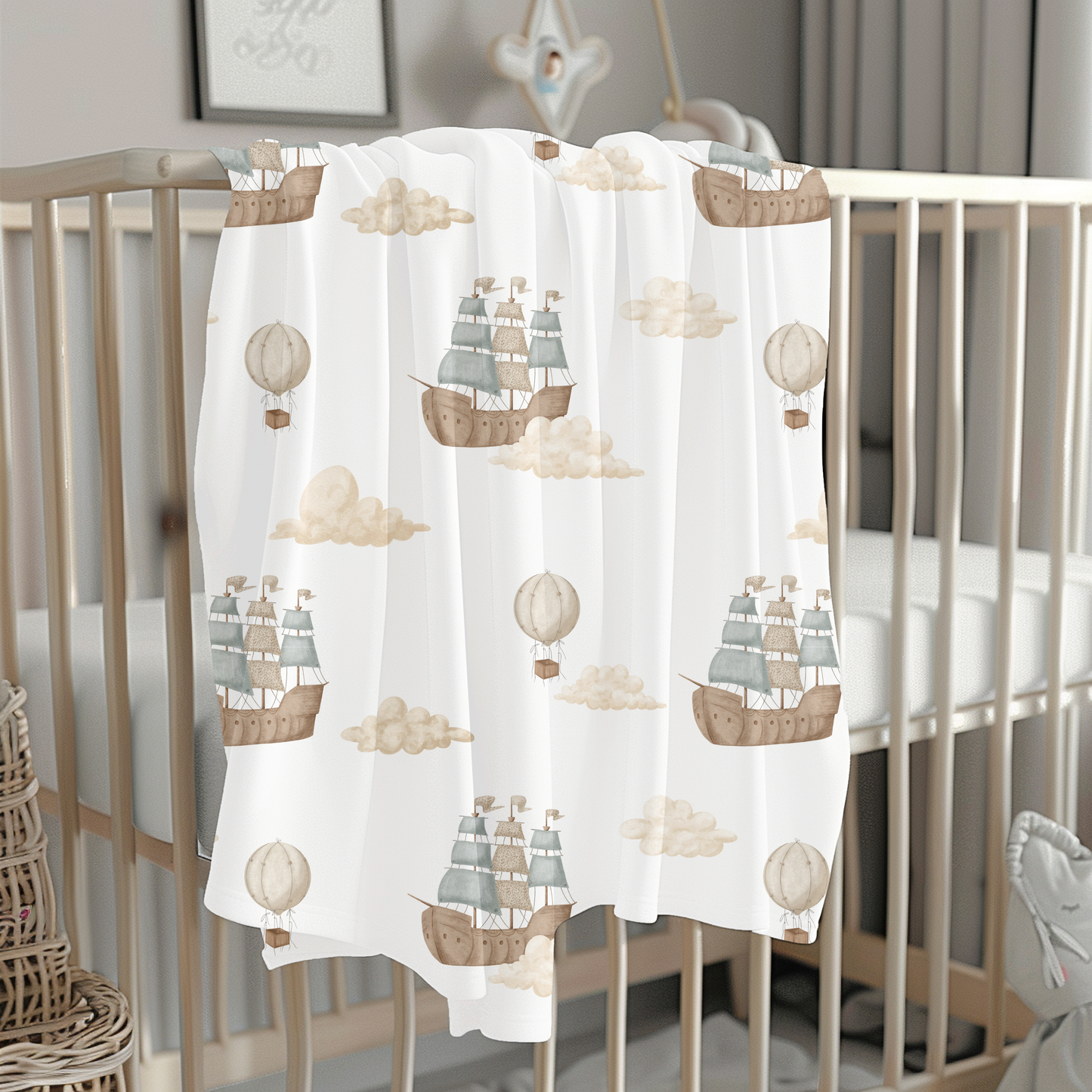 Baby crib with a decorative sheet featuring ship and hot air balloon patterns.