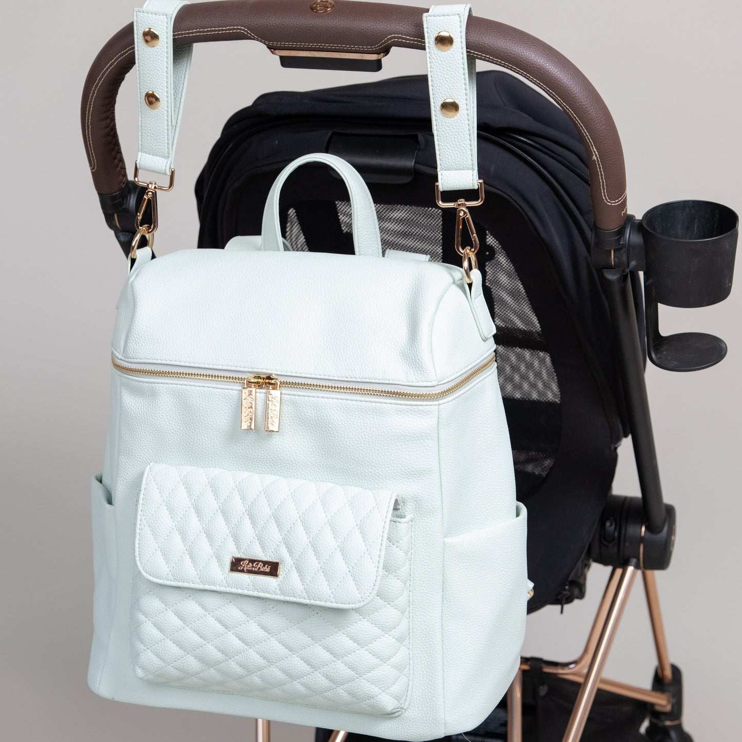 Light blue backpack with gold accents on a stroller