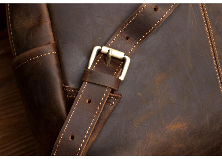 Close-up of a brown leather bag with a strap and buckle.