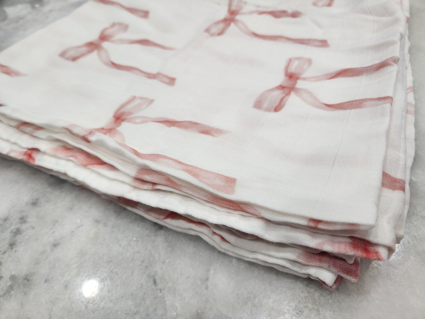 Folded fabric with red ribbon pattern on a marble surface