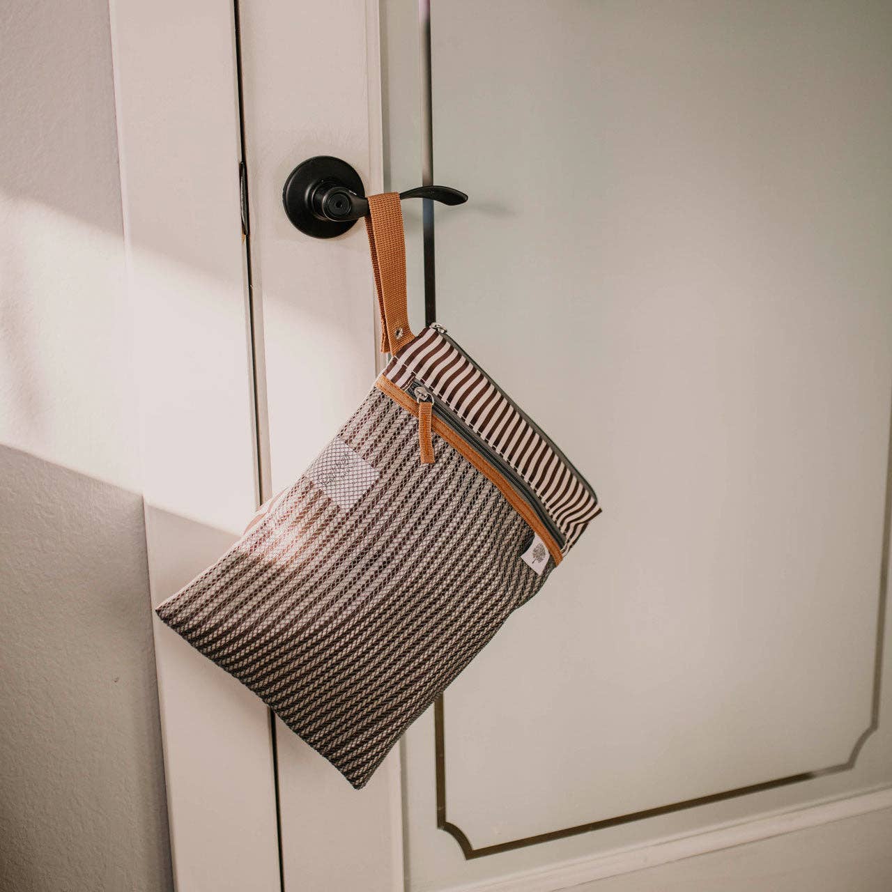 Striped pouch hanging on a door handle.