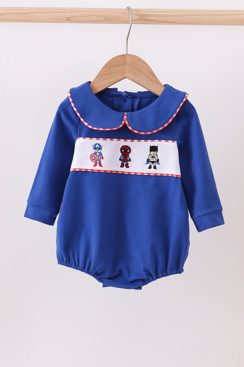 Blue baby romper with superhero design on a hanger against a white background
