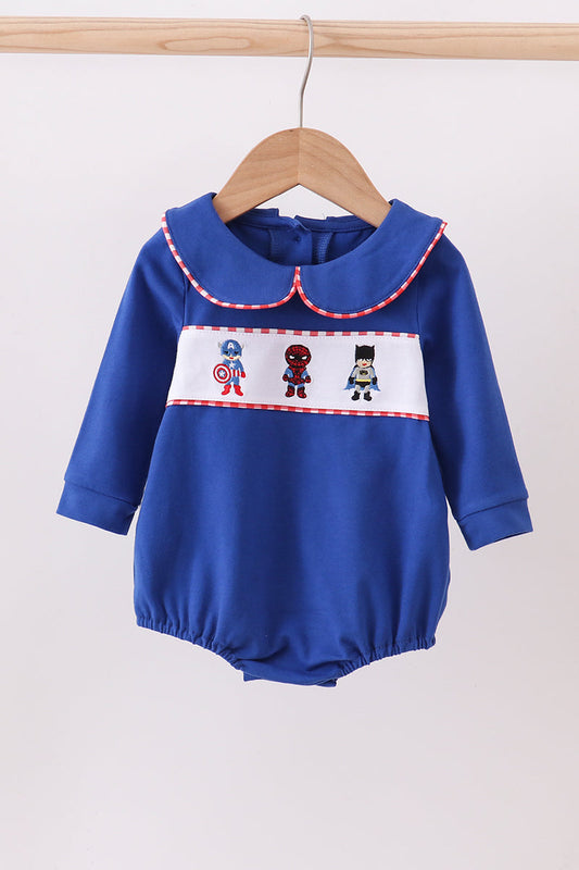 Blue baby romper with superhero design on a hanger against a white background