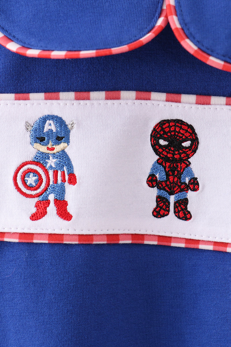 Embroidered superhero characters on a blue fabric with red and white checkered trim.