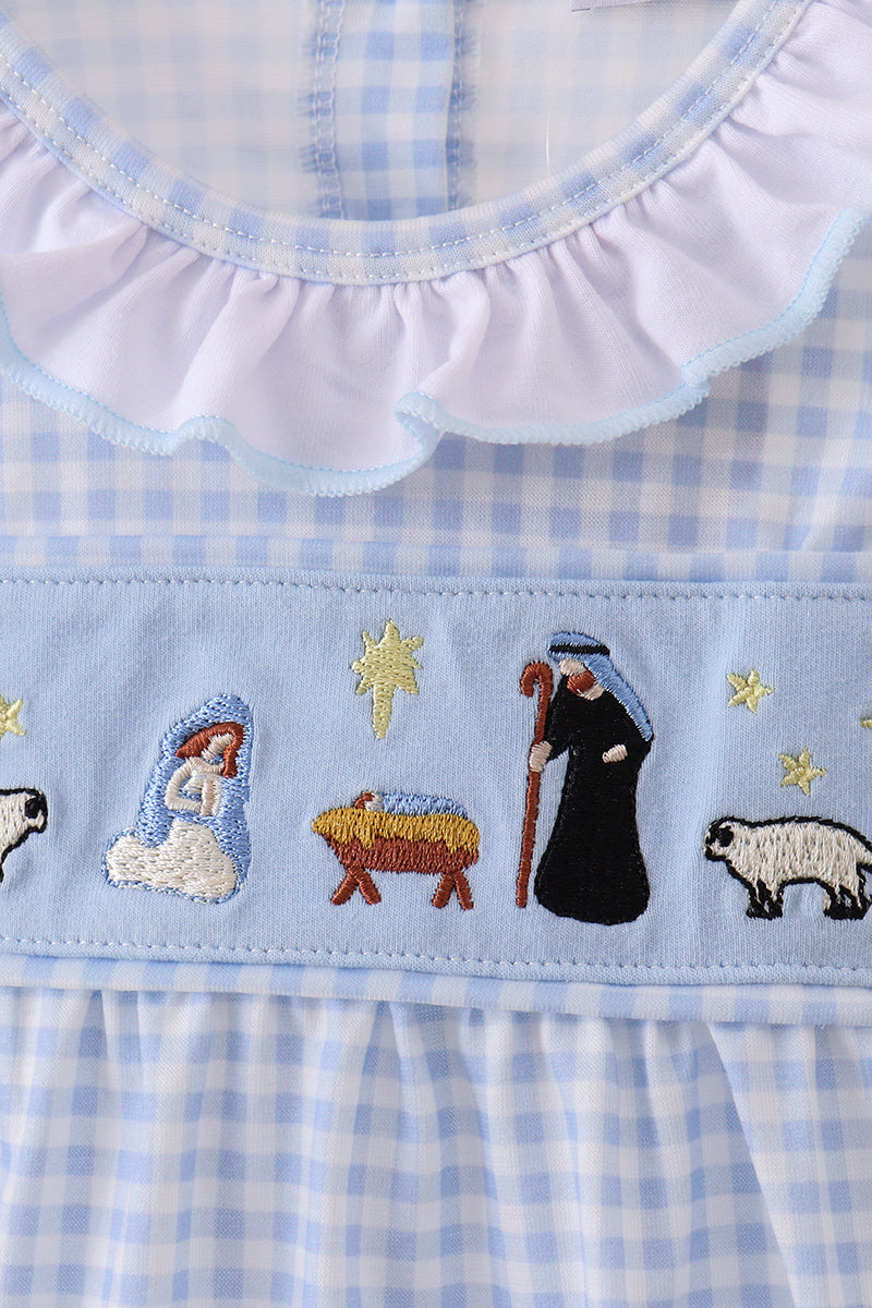 Baby dress with embroidered nativity scene on a blue checkered background