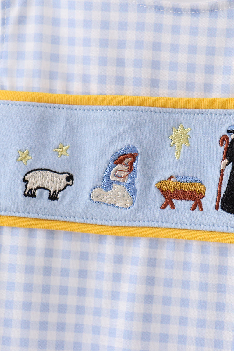 Embroidered nativity scene on a blue checkered fabric with yellow border