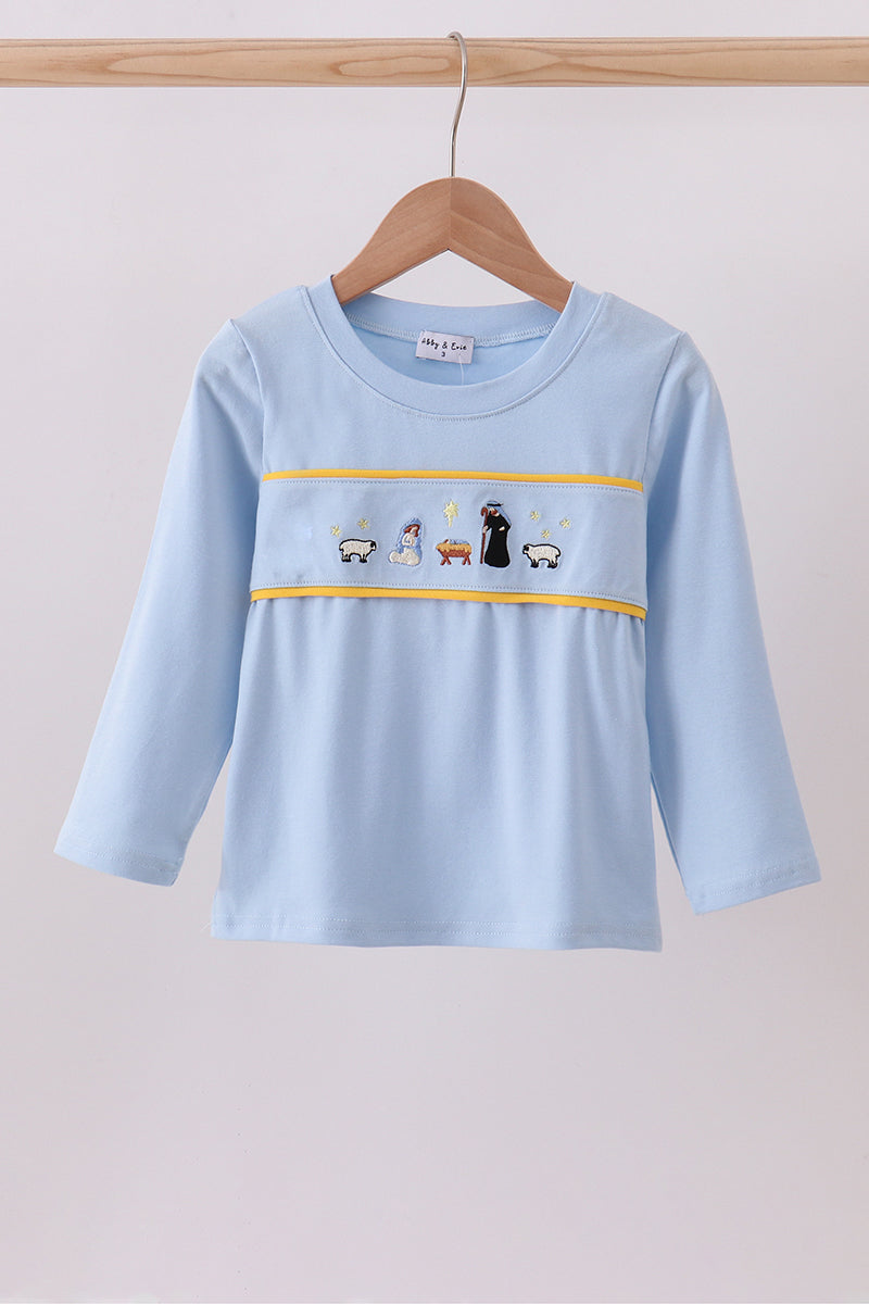 Light blue long-sleeve shirt with embroidered design on a wooden hanger against a light gray background