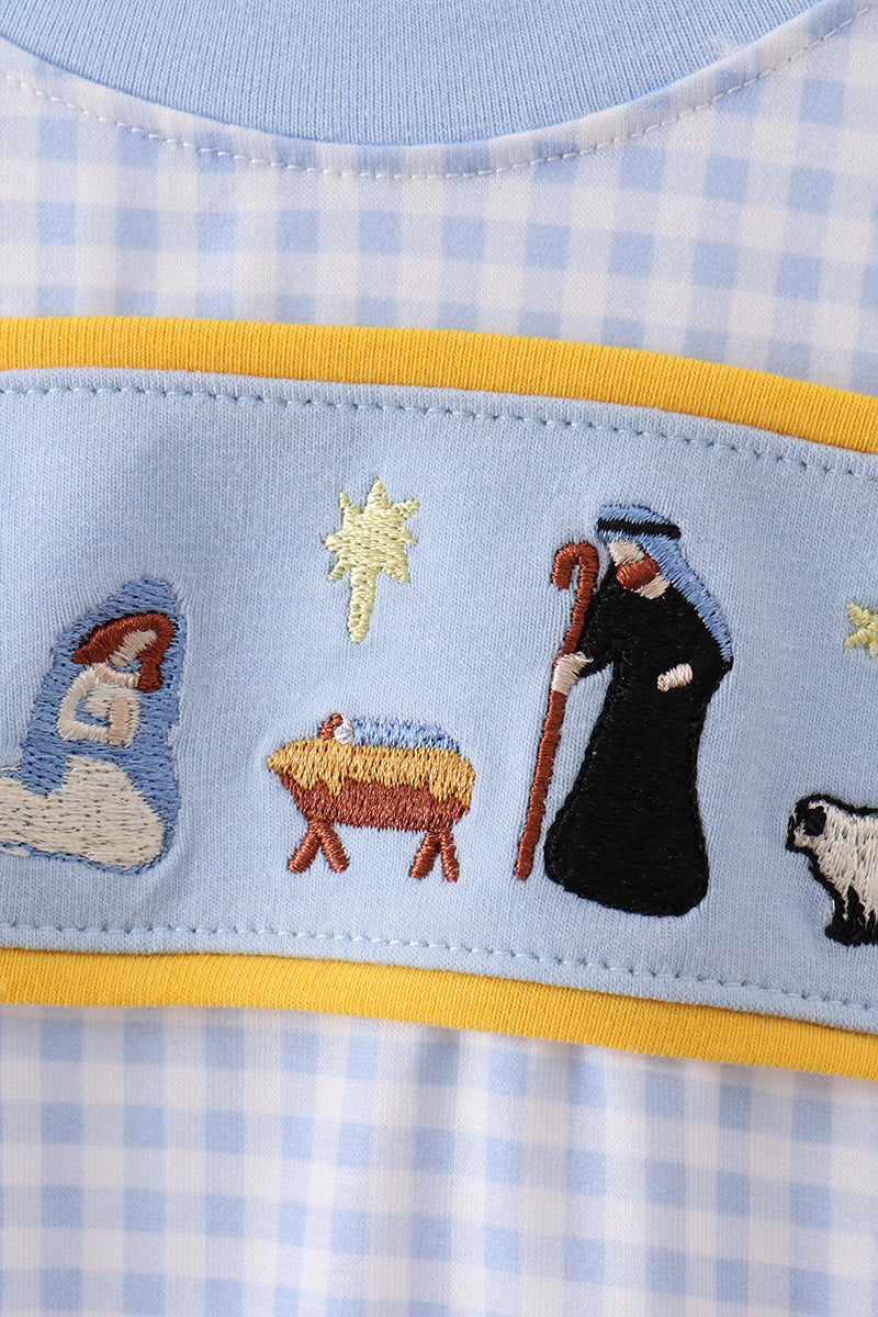 Embroidered nativity scene on a baby outfit with blue checkered pattern
