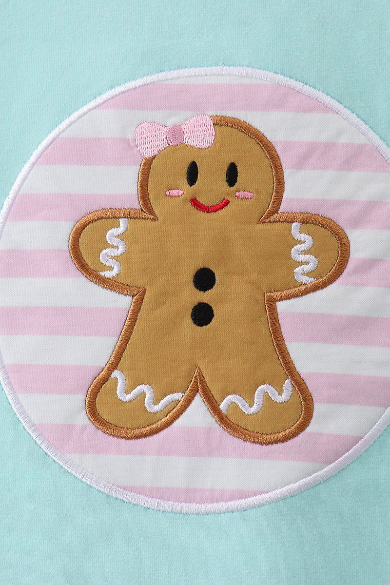 Gingerbread man with a pink bow on a pink and white striped background
