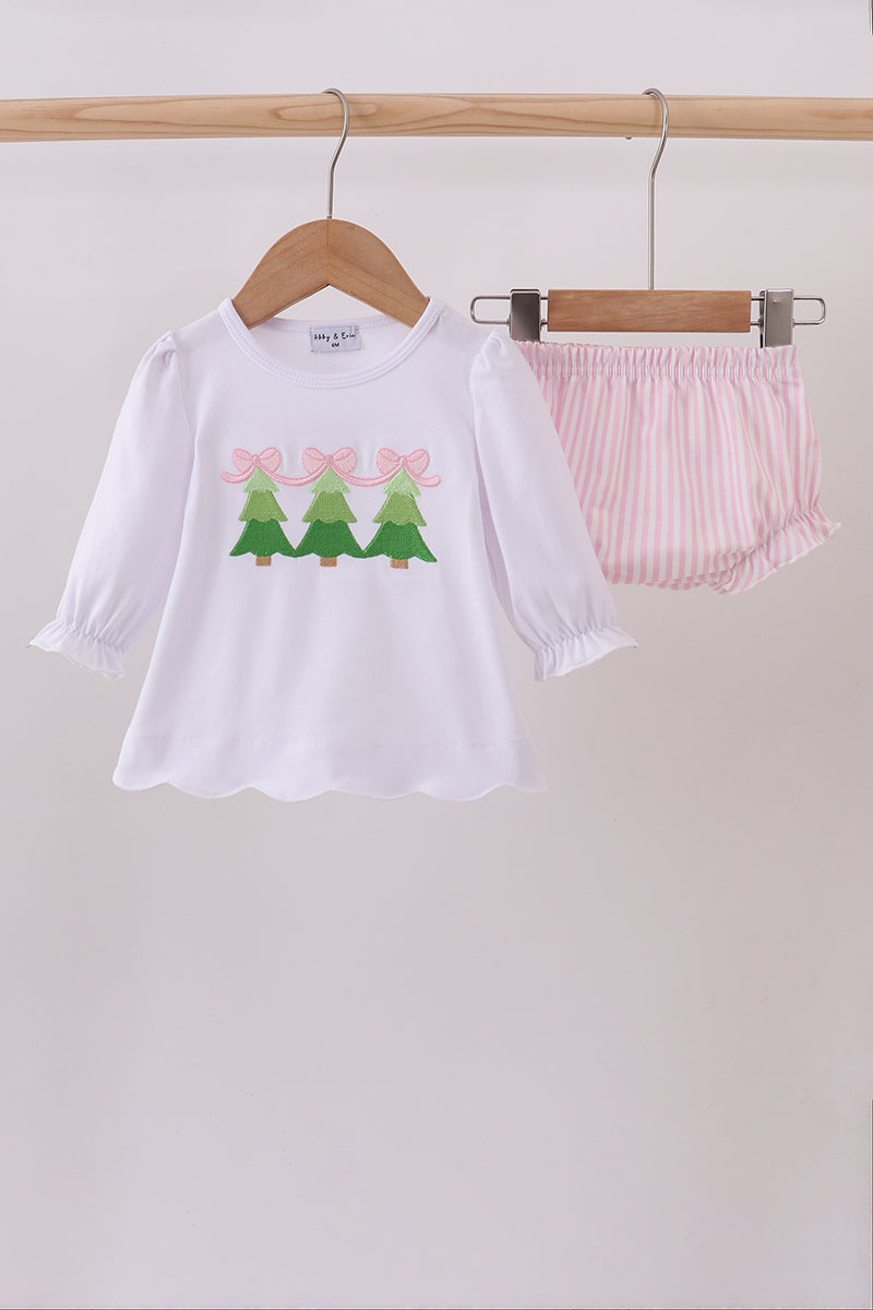 White shirt with tree design and pink shorts on hangers against a white background